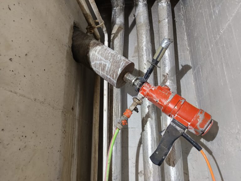 Bohrtechnik im Installationsbereich. Die Bohranlage ist in einem engen Bereich zwischen Leitungen und Bauteilen eingerichtet.