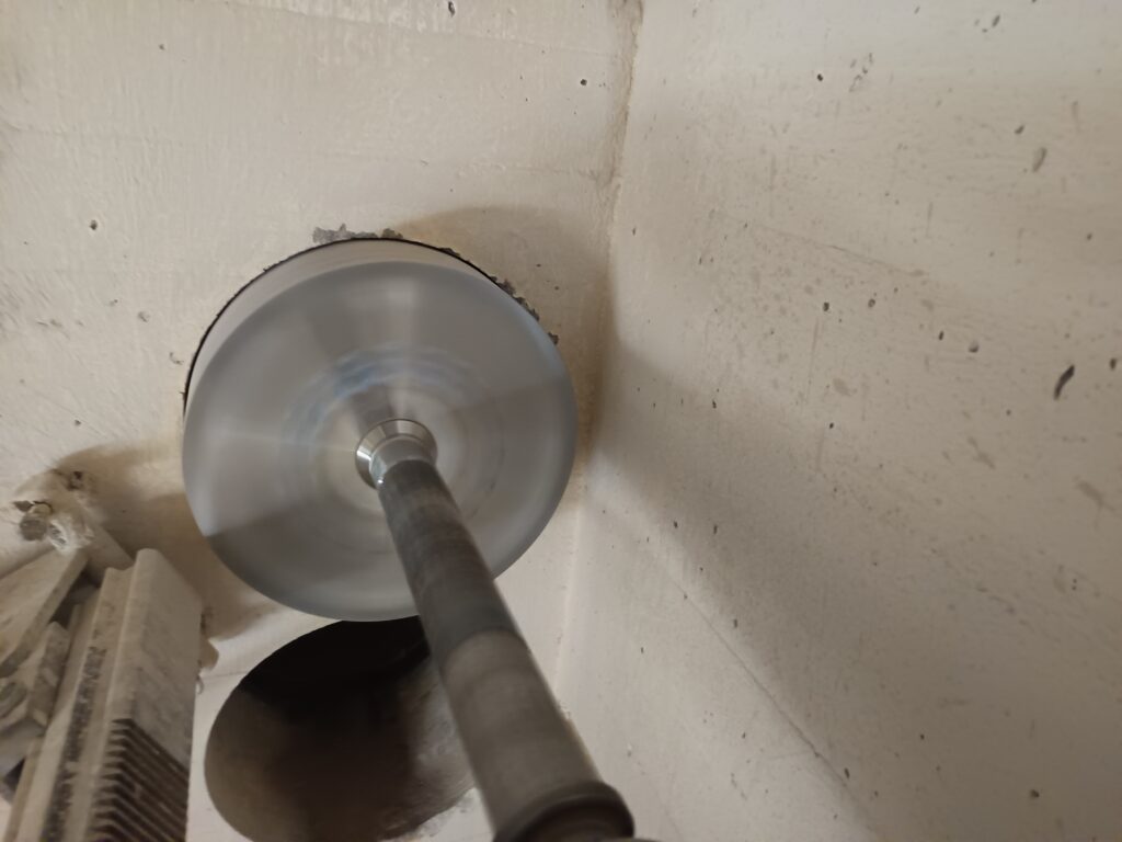 Eine fertige Kernbohrung Ø300 und eine weitere Kernbohrung Ø300 in Ausführung in einer ca. 50 cm starken Stahlbetonwand.