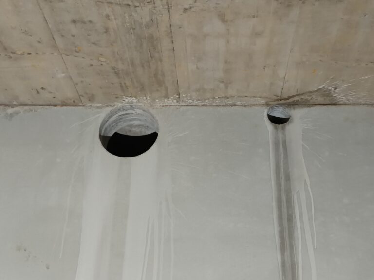 Ausgeführte Öffnungen im Rohbau. Mehrere runde Öffnungen zeigen das Ergebnis im unfertigen Innenbereich.